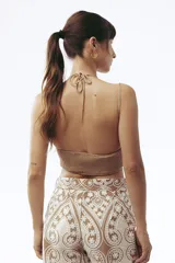 Crop top color beige con escote halter y elástico en la parte inferior.