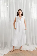 Vestido túnica midi sin mangas, color blanco, con cuello camisero y cierre frontal con botones.