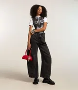 Pantalón de jean azul oscuro, corte barrel, con cintura con trabillas, cierre con botón y cremallera, bolsillos delanteros y traseros, y recortes en las rodillas y el bajo.