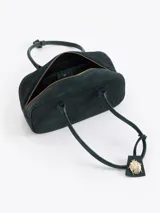 Cartera rectangular de estructura firme confeccionada en cuero descarne vacuno color marrón. Presenta manijas fijas, cierre superior y un charm metálico dorado en forma de vaquita de San Antonio colgando de un tag lateral. Incluye el logo de la marca grabado en relieve en el frente.