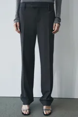 Pantalón de vestir gris oscuro de tiro bajo, con trabillas en la cintura, bolsillos delanteros y traseros, raya planchada y pierna recta.