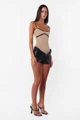Short negro de cuerina con cierre diagonal desmontable, tiro medio y broches snap en el delantero.
