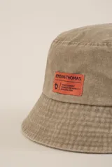 Gorro tipo bucket color lila con etiqueta naranja con el logo de la marca Benson & Thomas.