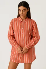 Camisa color ladrillo con rayas verticales blancas, de corte holgado, con cuello camisero, cierre con botones y mangas largas.