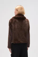 Chaqueta corta negra de piel sintética con cuello clásico, cierre frontal con cremallera y mangas largas.