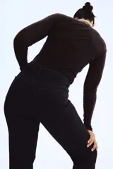 Jean tobillero de denim negro lavado, tiro alto, con cinco bolsillos y cierre de botón. Corte ajustado en cadera y muslo, con pierna recta y levemente ceñida en el bajo.