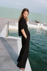 Pantalón negro de tiro alto con cintura elástica ajustable con cordones, bolsillos delanteros y pernera ancha.