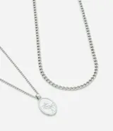 Set de dos collares plateados de metal. Uno es una cadena gruesa de eslabones y el otro es una cadena fina con un dije ovalado con dos palmeras grabadas.