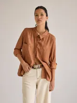 Camisa color marrón de lino y viscosa, de corte clásico, con cuello camisero, cierre frontal con botones, mangas largas con puños abotonados y dos bolsillos de parche en el pecho.