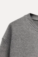 Sweater color crema de tejido suave, con cuello redondo en rib y mangas largas sin costuras.