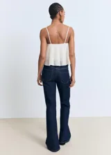 Top corto color crema, sin mangas y con tirantes finos. Presenta un diseño con volante fruncido en el escote y el bajo.