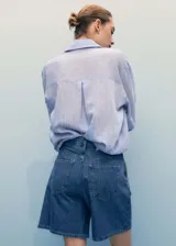 Short de jean azul de tiro medio, con pinzas delanteras, cierre frontal con cremallera y botón, y bolsillos laterales.