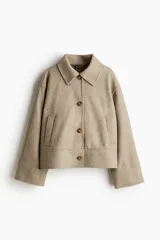 Campera corta color beige de tejido de fieltro suave con cuello clásico y cierre frontal con botones. Modelo de corte holgado con hombros caídos, bolsillos insertados y sin forro.