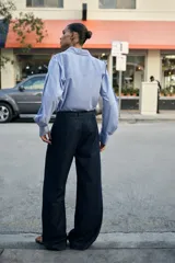 Jeans de tiro alto con corte bootcut, confeccionados en denim azul oscuro. Presentan costuras verticales decorativas en el frente, bolsillos laterales y cinturón del mismo tejido con hebilla metálica.