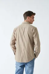 Camisa de pana color verde militar, de corte regular, con cuello clásico y cierre frontal con botones.