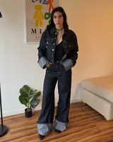 Campera corta de jean azul oscuro con cuello clásico, cierre con botones metálicos y bolsillos frontales.