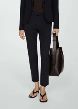 Pantalón negro de vestir, de corte recto y tiro medio, con cierre de cremallera y gancho.