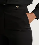 Pantalón flare negro confeccionado en viscosa, con botón en forma de corazón y abertura en los laterales.