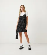 Vestido corto negro con estampado de palabras en blanco y remera blanca de manga corta con estampado de estrellas.