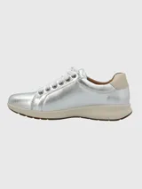 Zapatilla urbana de cuero color dorado, con cordones y suela blanca.