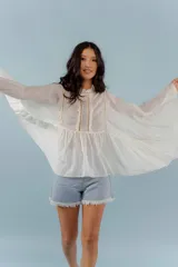 Camisa blanca de mangas largas con puntillas y cuello mao.