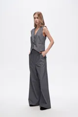 Pantalón gris de poliéster, corte ancho y tiro alto, con bolsillos laterales.