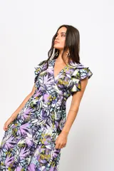 Vestido largo con estampado floral en tonos lila, verde y blanco, con escote en V, mangas cortas con volados y lazo ajustable en la cintura.