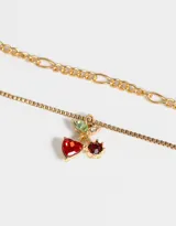 Collar doble con cadenas doradas de diferentes diseños. La cadena más corta tiene dijes de cerezas con strass rojos y verdes. Cierre de mosquetón.