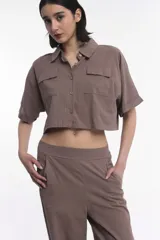 Camisa corta color marrón con cuello clásico, cierre frontal con botones, mangas cortas con dobladillo y dos bolsillos de parche en el pecho.