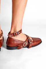 Chatas de cuero color marrón con tiras cruzadas con hebillas y tachas plateadas.