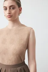 Top sin mangas de color negro con textura floral en relieve, cuello redondo y diseño estructurado.