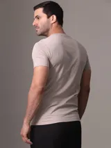 Remera color gris topo de manga corta y cuello redondo, con logo "Calvin Klein Jeans" estampado en plateado en el pecho.