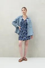 Vestido corto azul con estampado de hojas, escote en V y botones decorativos en el frente. Su cintura marcada y mangas relajadas equilibran frescura y estructura, mientras que el estampado aporta un aire bohemio y moderno ideal para el día o la tarde.