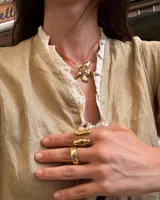 Collar artesanal con dije de flor plateada, realizado con hilo de seda natural teñido a mano.