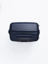 Valija rígida de viaje color azul marino con diseño de líneas horizontales en relieve. Tiene manija retráctil de aluminio, cuatro ruedas con giro de 360°, cierre con combinación y manija lateral. Interior forrado con divisor y bolsillo de malla.