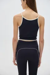 Top deportivo corto negro con cuello halter y tirantes finos en color crema.