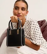 Bolso transversal pequeño tipo bandolera, color negro con detalles en blanco y herrajes dorados. Tiene correa de mano, asa larga desmontable y cierre superior.