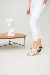 Sandalias bajas color crema con tres tiras en la capellada, una de ellas con textura tipo piel de cocodrilo. Pulsera con hebilla para ajustar al tobillo y taco cuadrado color negro.