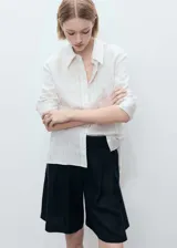 Short negro de lino con tiro medio, trabillas, cierre frontal con cremallera y botón, detalle de pinzas, cinturón con hebilla, diseño corto y recto, y dos bolsillos laterales.