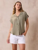 Camisa verde oliva de manga corta con cuello con solapa y abertura central con botones. Tiene un bolsillo aplicado en el pecho.