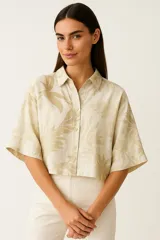 Camisa color crema con estampado de hojas en tonos beige, de corte crop, manga corta y cuello camisero.