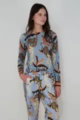 Sweater celeste de cashmere con estampado de tigres y hojas en tonos marrones y beige.