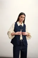 Chaleco de jean celeste con efecto lavado, sin mangas, con cuello redondo y cierre frontal con botones.