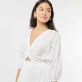 Vestido largo blanco con bordado inglés, escote en V, mangas 3/4 y corte en la cintura con abertura.