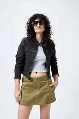 Minifalda color marrón claro, de corte recto con cierre metálico visible al frente y bolsillos decorativos con tachas.