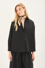 Camisa beige de poplin amplia, con botones laterales para abotonar de forma cruzada.