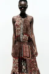 Vestido largo con estampado cachemir en tonos marrones, cuello halter con cordones con abalorios, nido de abeja elástico en la cintura, forro interior y tejido con hilo metalizado.