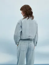 Campera de jean azul claro con cuello mao, cierre con botones metálicos y costuras a contraste.