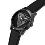 Reloj analógico Guess modelo Clark, con caja redonda negra y correa de silicona negra. La esfera negra presenta un gran triángulo plateado con diseño geométrico en su interior, y las agujas son plateadas.