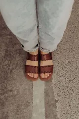 Sandalias de cuero marrón con tiras tejidas a mano y costuras a la vista, con base plana.